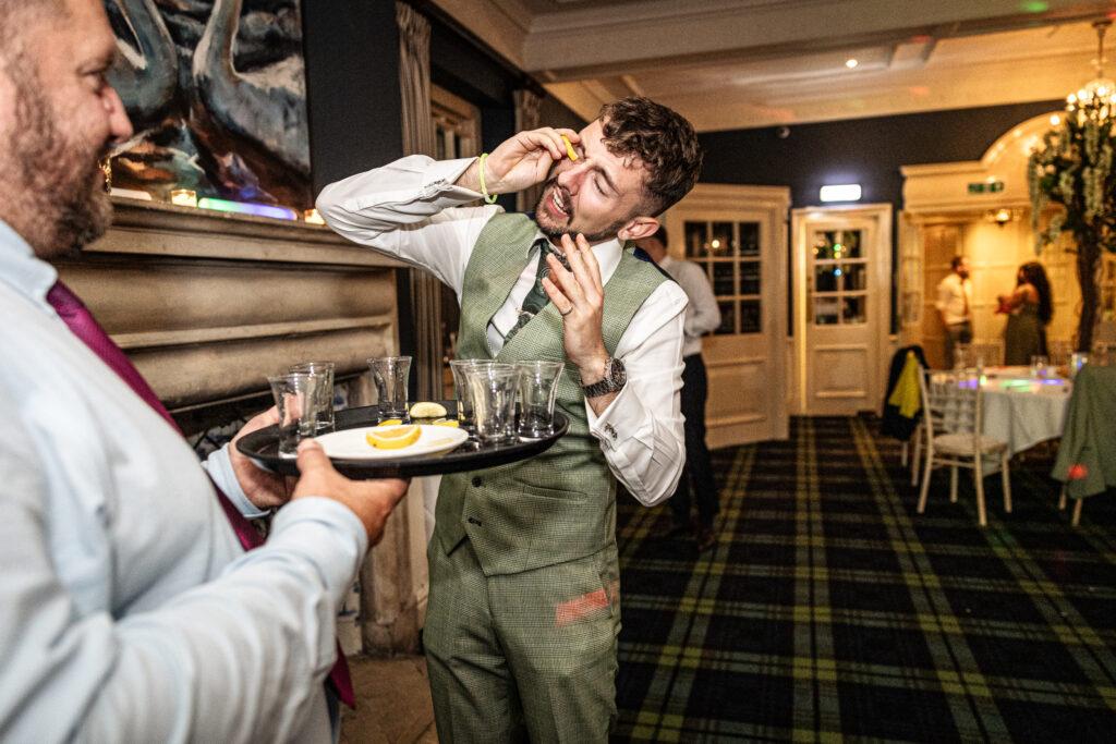 Alternative Wedding Photography of man taking shot in his eye.